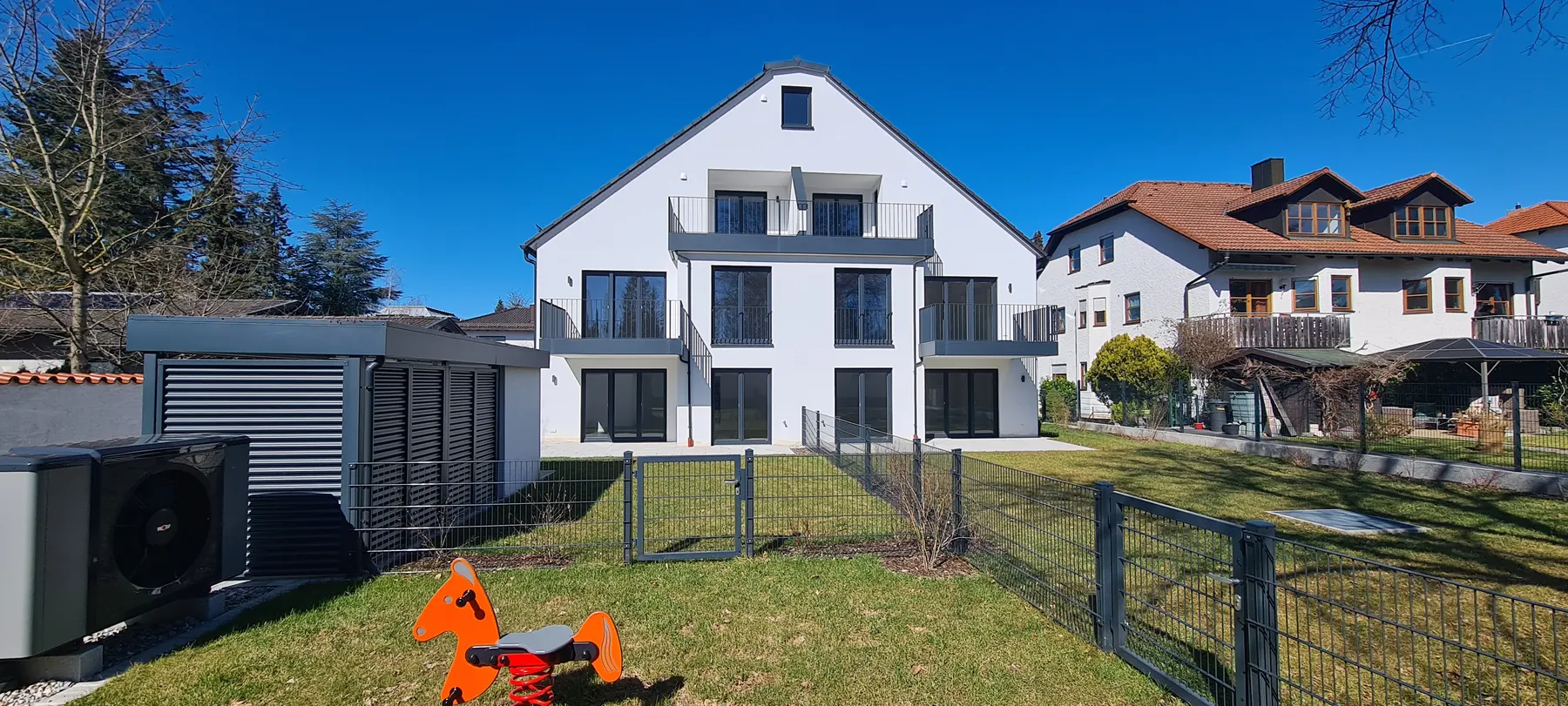 Fertiggestelltes Mehrfamilienhaus Glockenblumenstraße 31 von der Gartenseite mit Balkonen